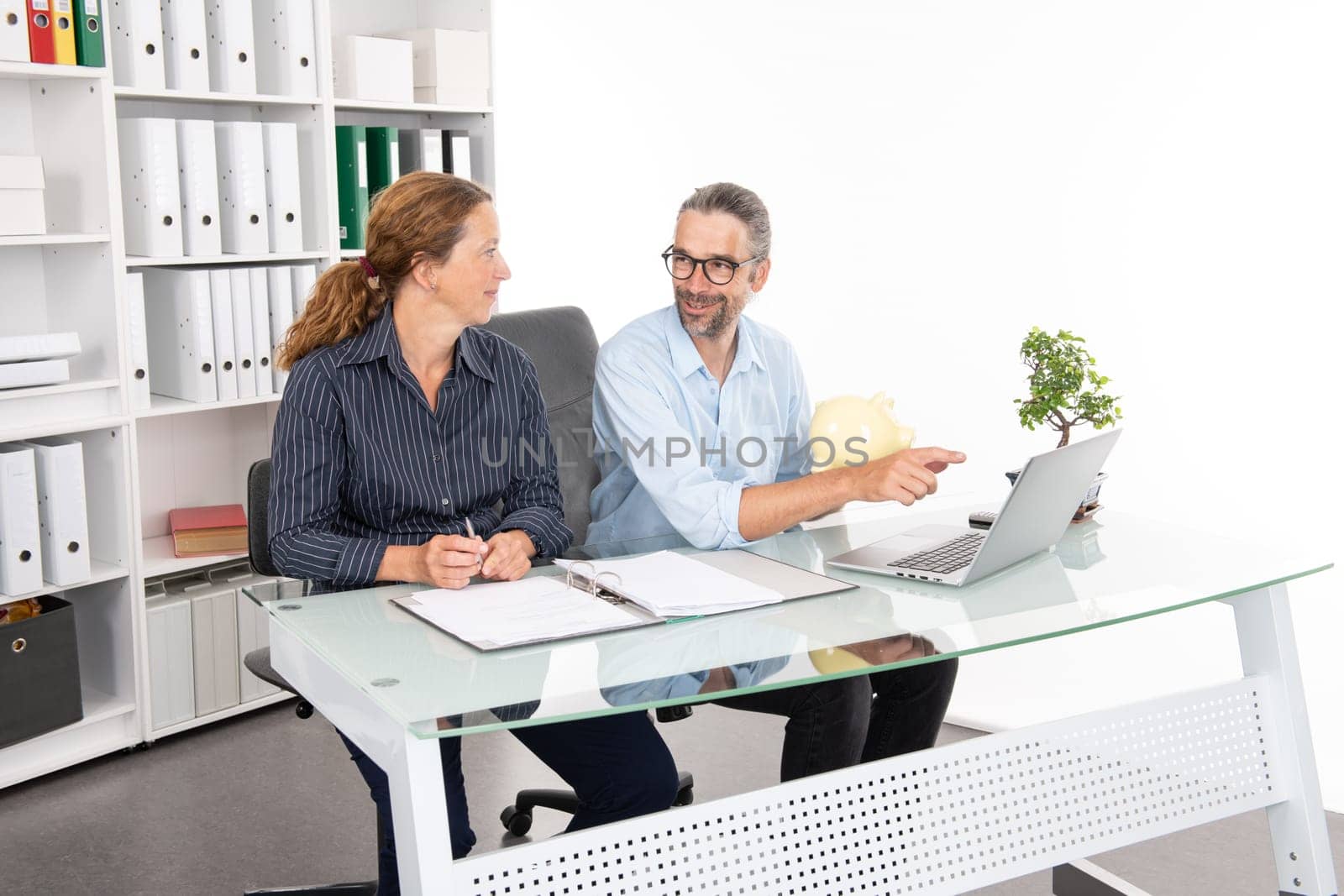 young businessman with piggy bank and businesswoman together in the office