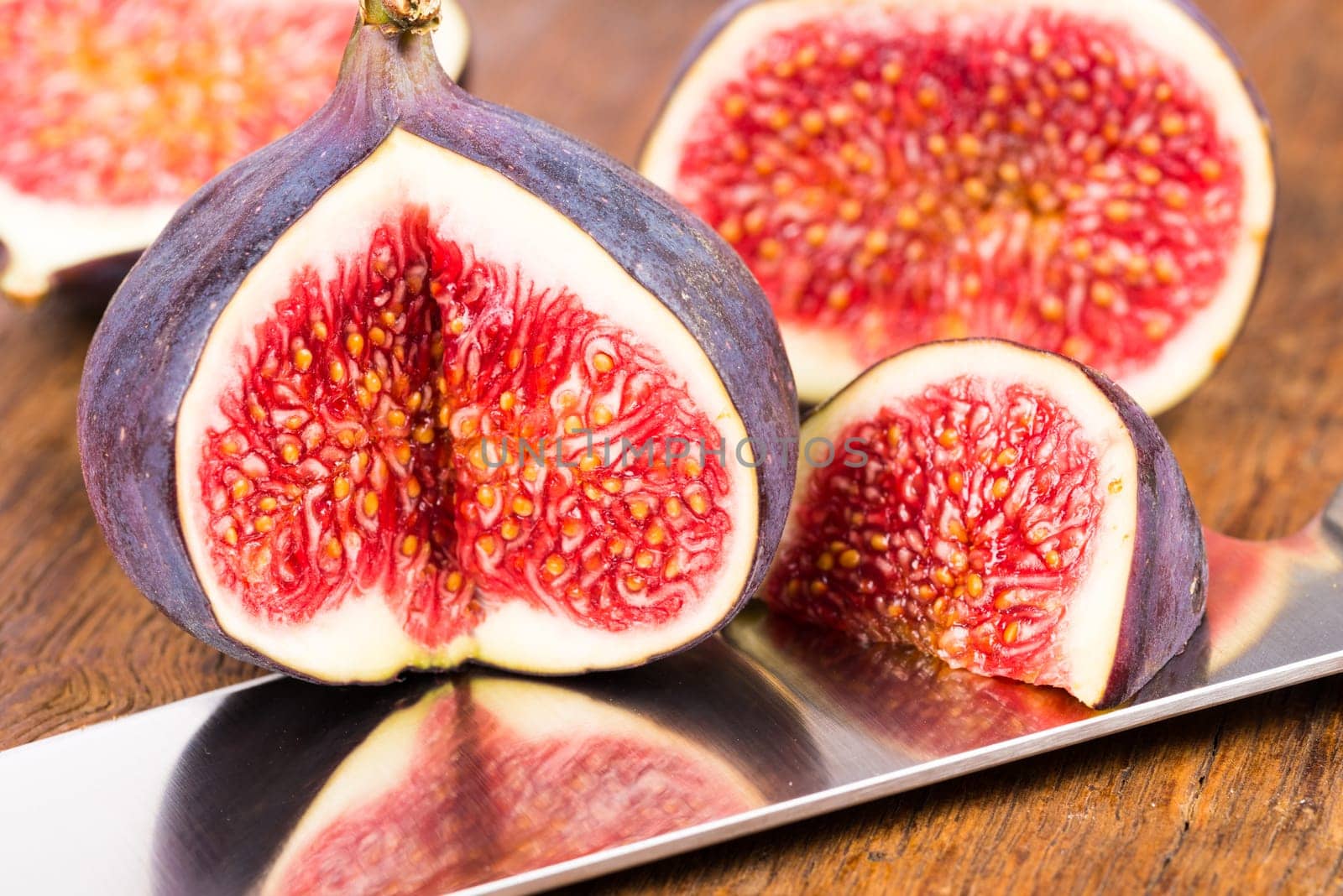 Group of sliced ripe, delicious and sweets figs with a kitchen knife on a old rustic wooden cutting board