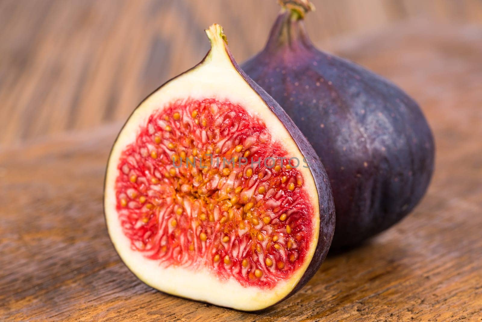 One whole and on half sliced ripe, delicious and sweets figs on a old rustic wooden cutting board