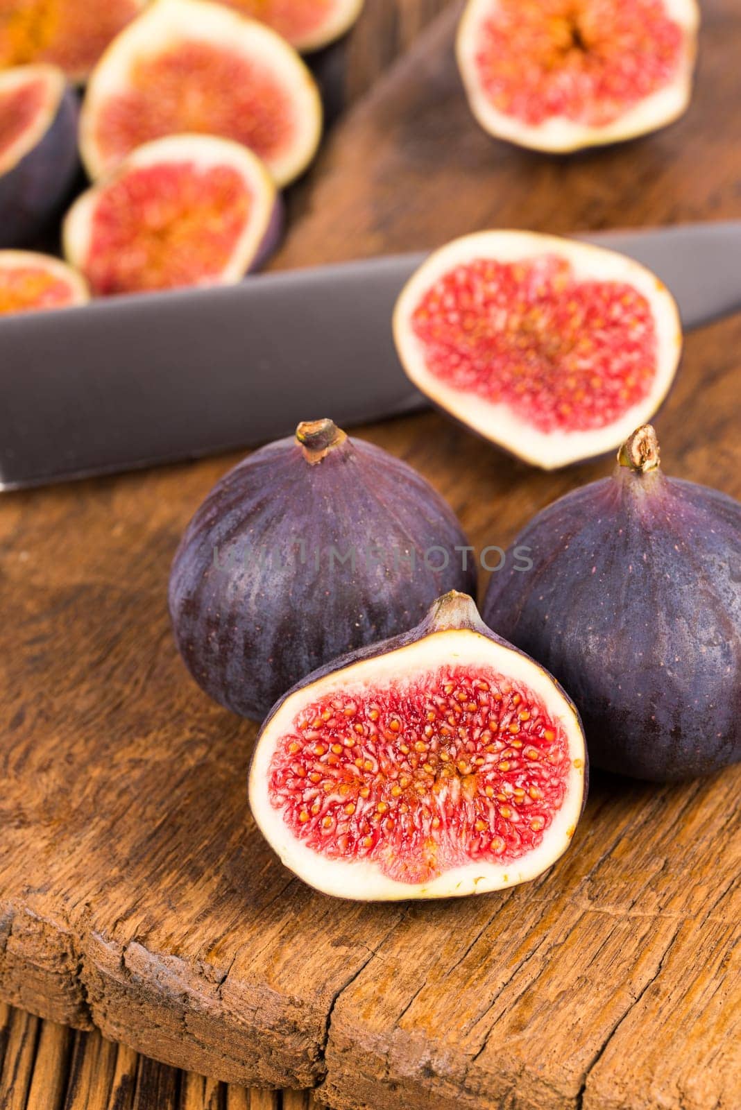 Group of whole and sliced ripe, delicious and sweets figs with a kitchen knife on a old rustic wooden cutting board