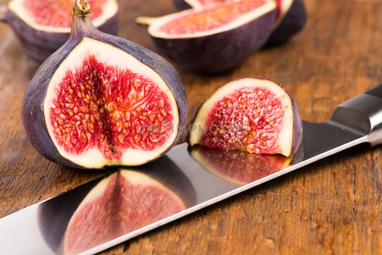 Group of sliced ripe, delicious and sweets figs with a kitchen knife on a old rustic wooden cutting board