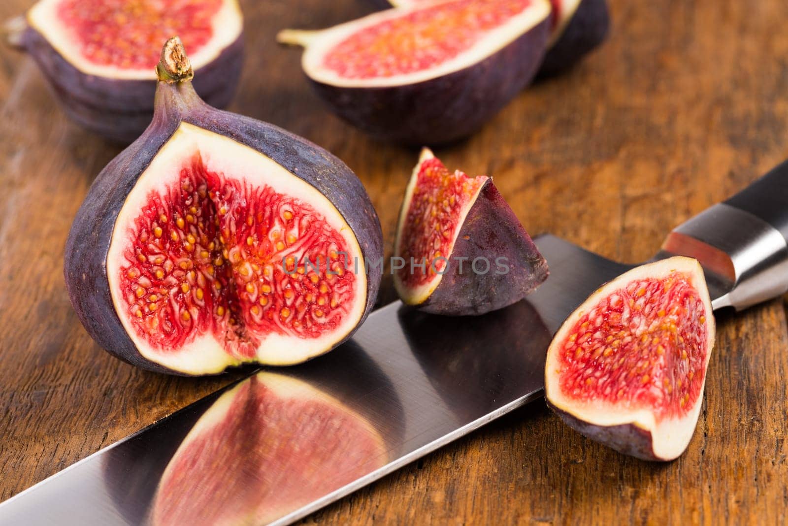 Group of sliced ripe, delicious and sweets figs with a kitchen knife on a old rustic wooden cutting board