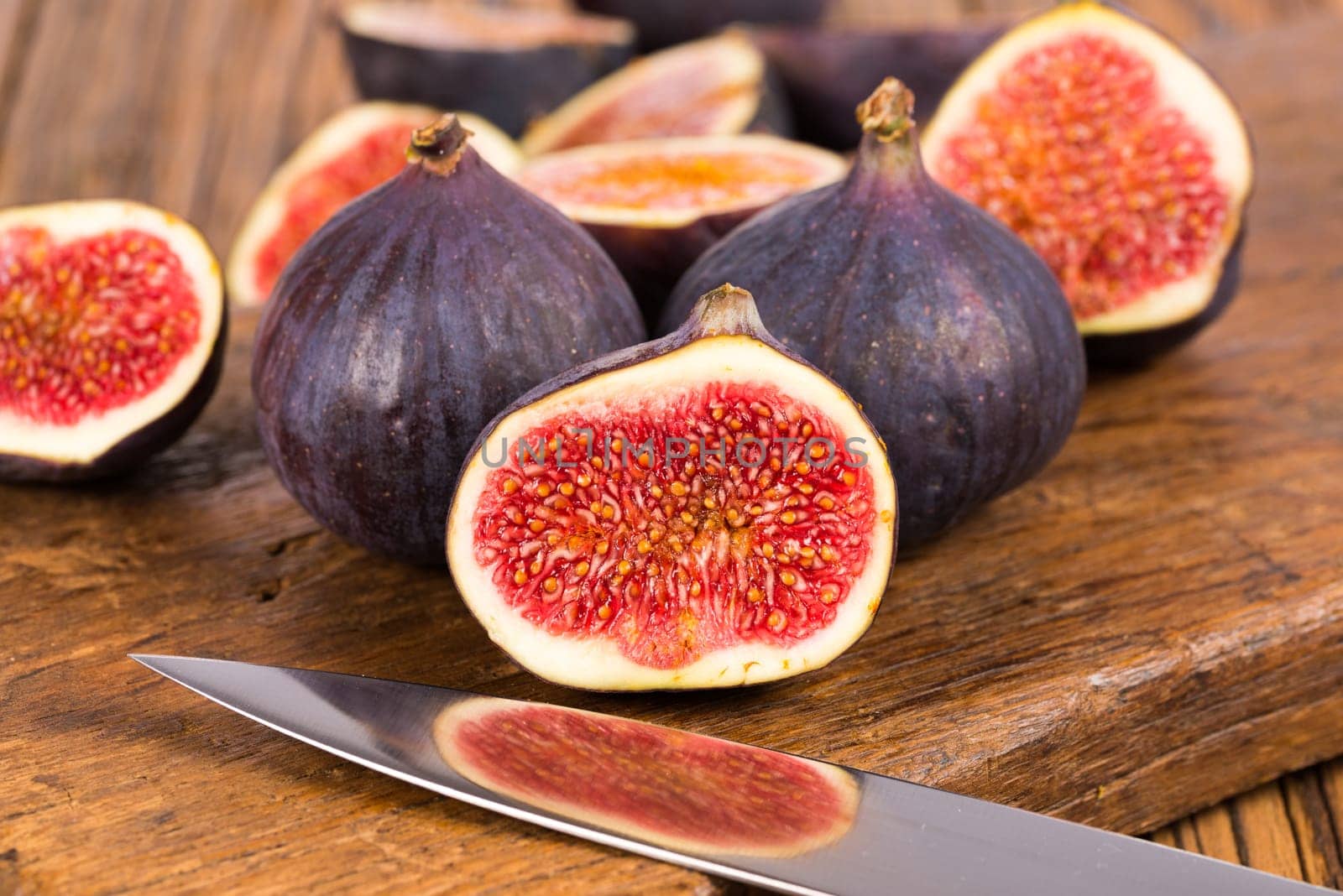 Group of whole and sliced ripe, delicious and sweets figs with a kitchen knife on a old rustic wooden cutting board