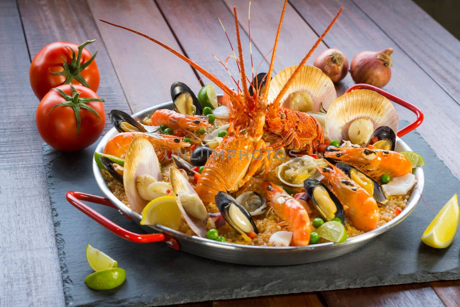 Gourmet seafood Valencia paella with fresh langoustine, clams, mussels and squid on savory saffron rice with prawn, scollops, mussels and lime slices, close up view