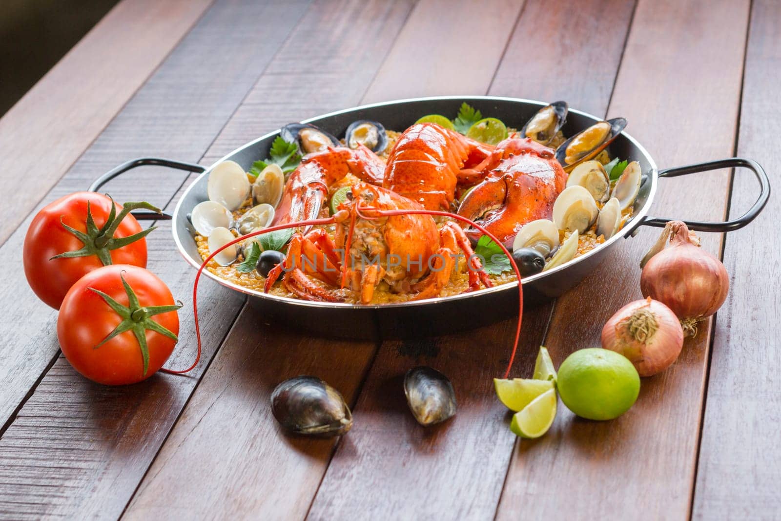 Gourmet seafood Valencia paella with fresh langoustine, clams, mussels and squid on savory saffron rice with peas and lemon slices, close up view