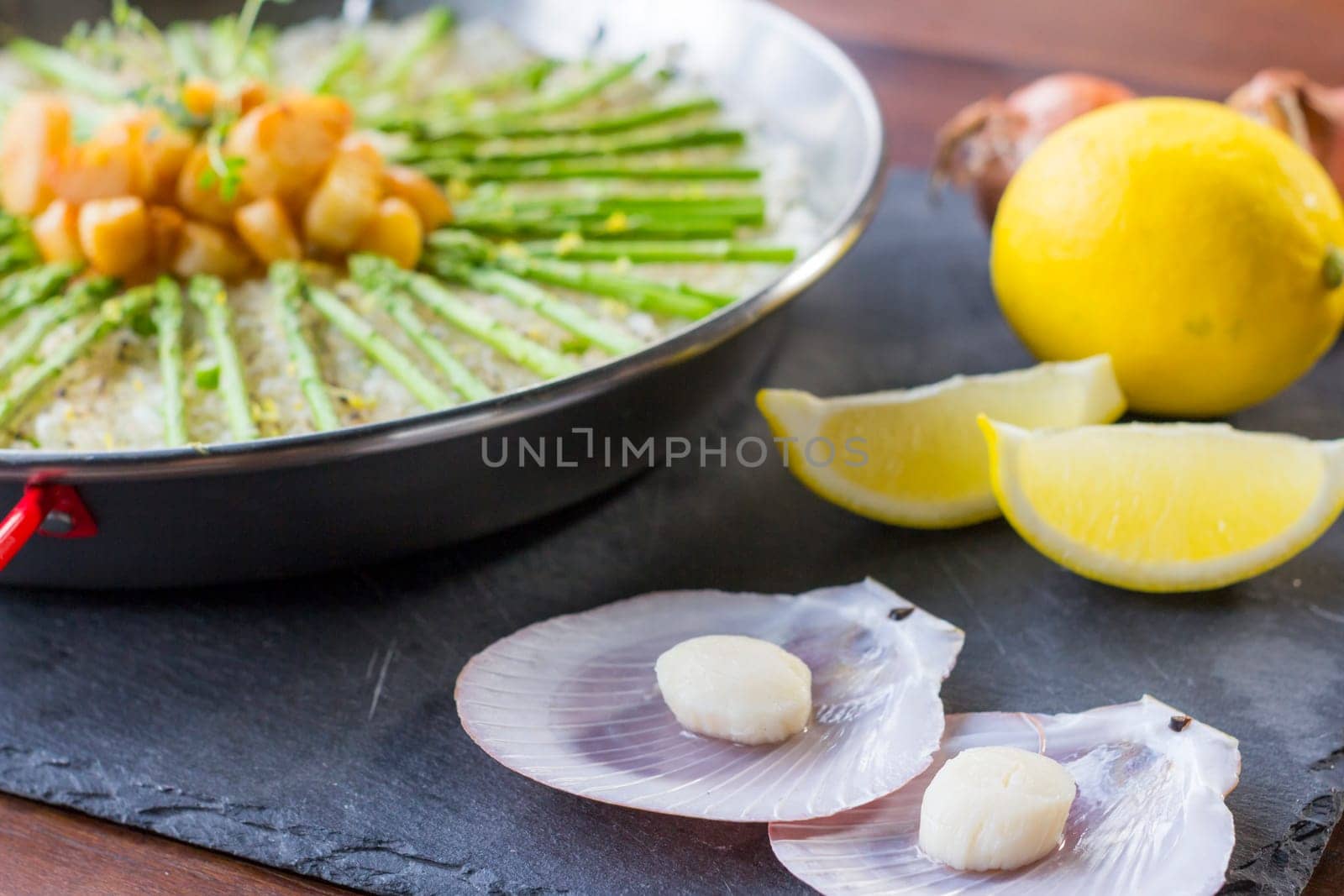 Paella with scollops and asparagus in traditional pan.