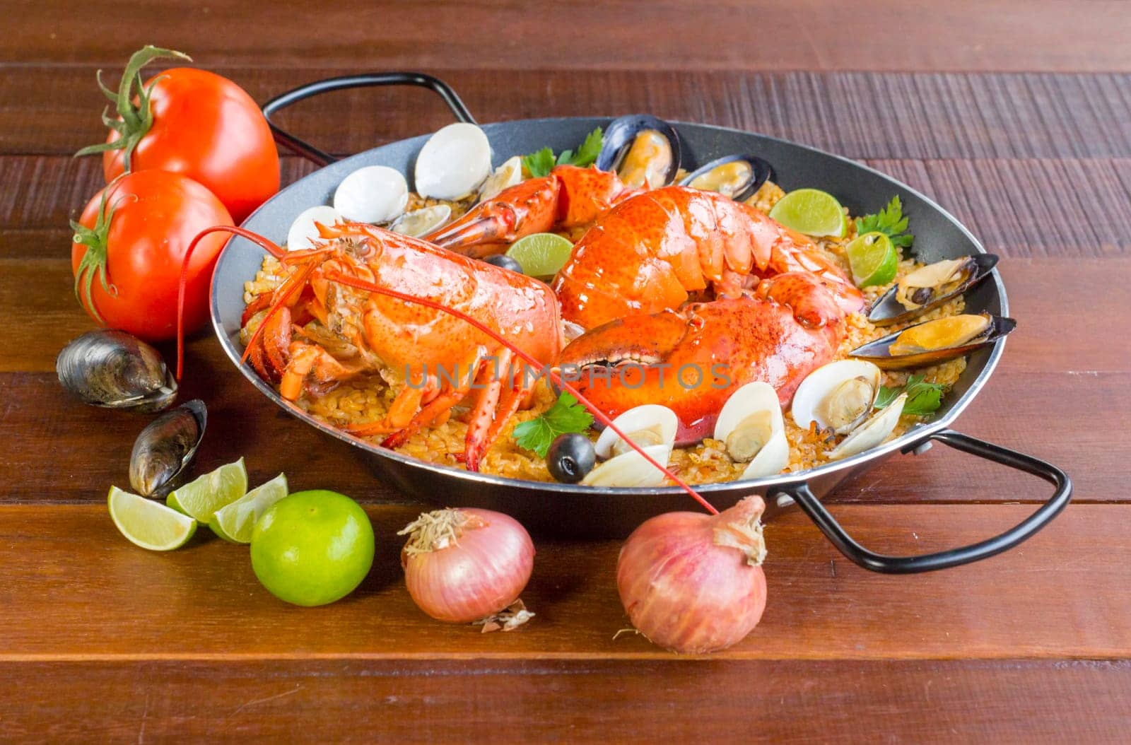 Gourmet seafood Valencia paella with fresh langoustine, clams, mussels and squid on savory saffron rice with peas and lemon slices, close up view