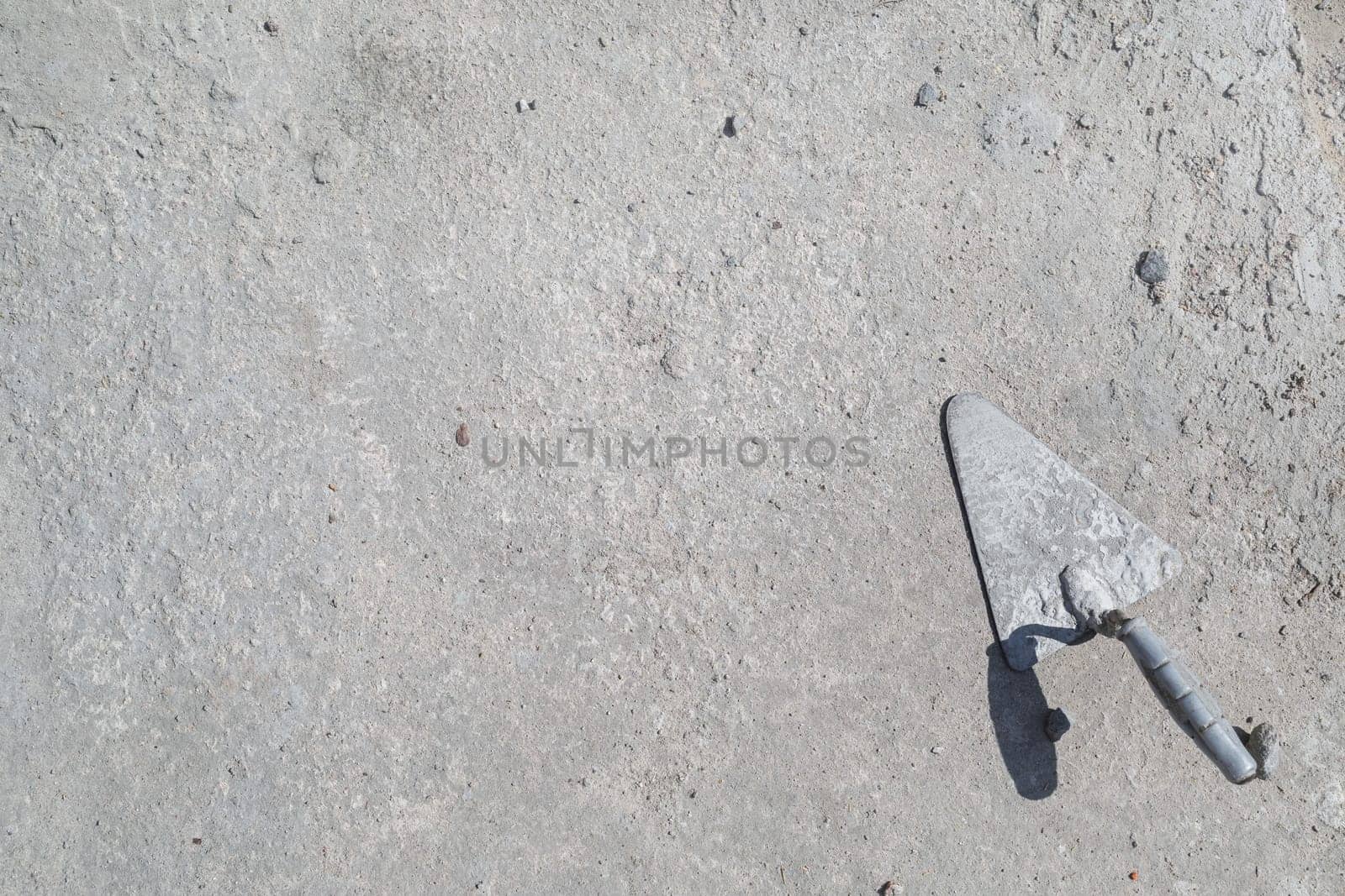 Used masonry trowel on concrete background. Space for text. Flat lay.