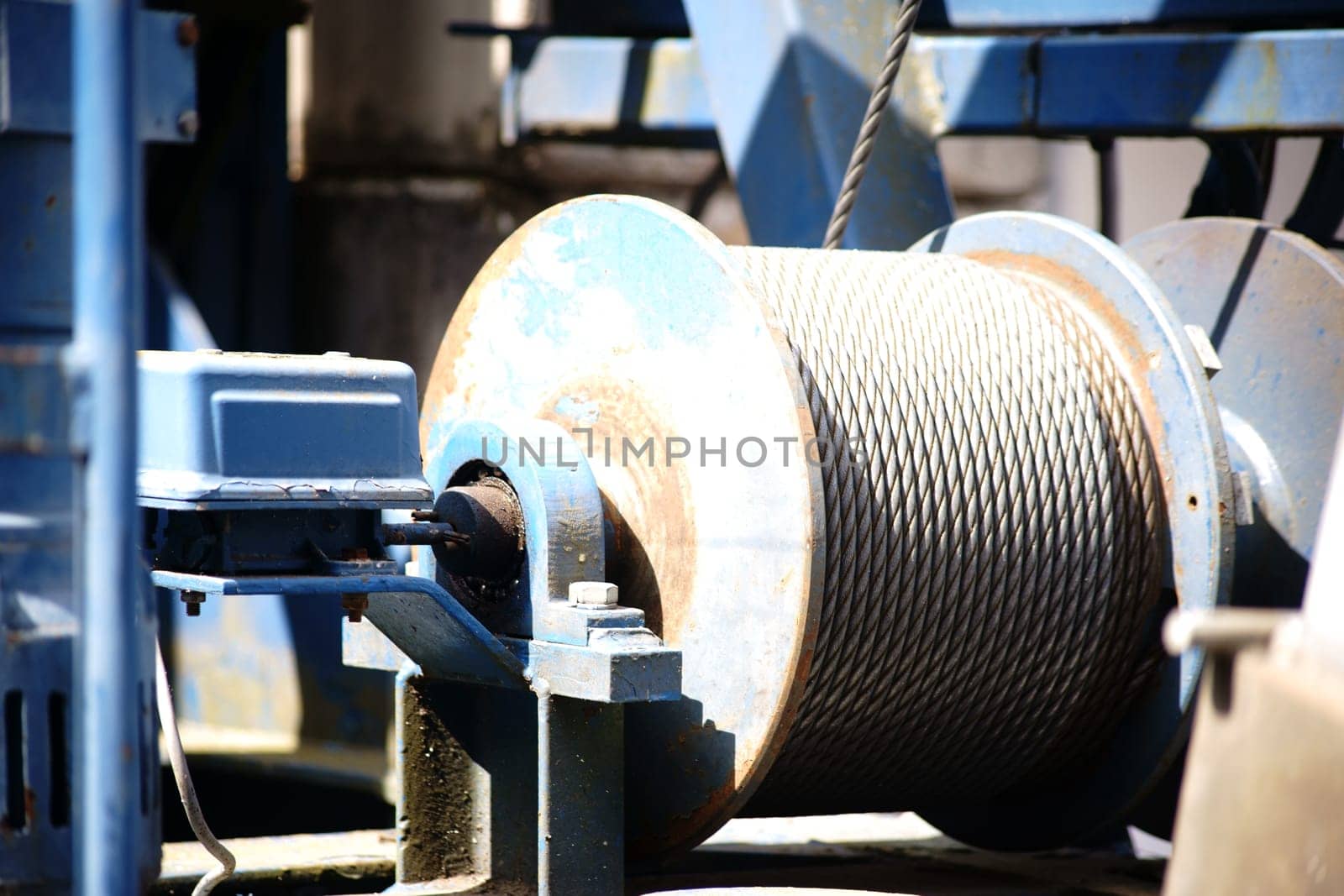 The close-up of the winch of a crane with a coiled steel rope.
