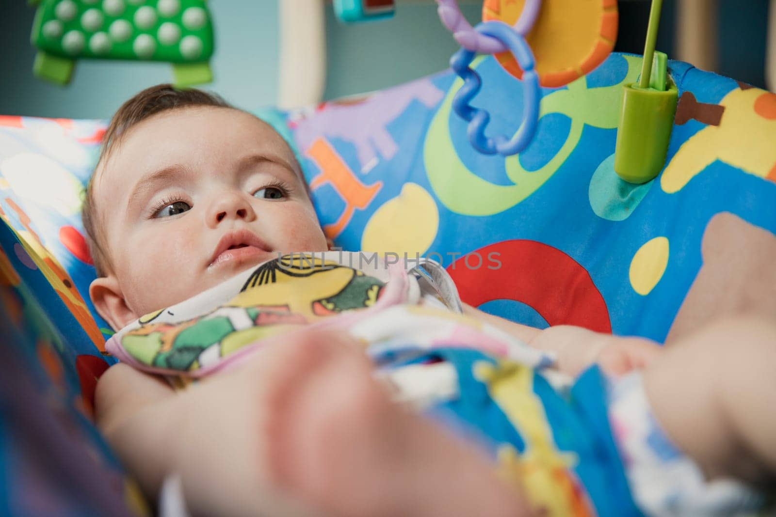 Low angle, close-up view of a baby girl lying in a baby bouncer relaxing.
