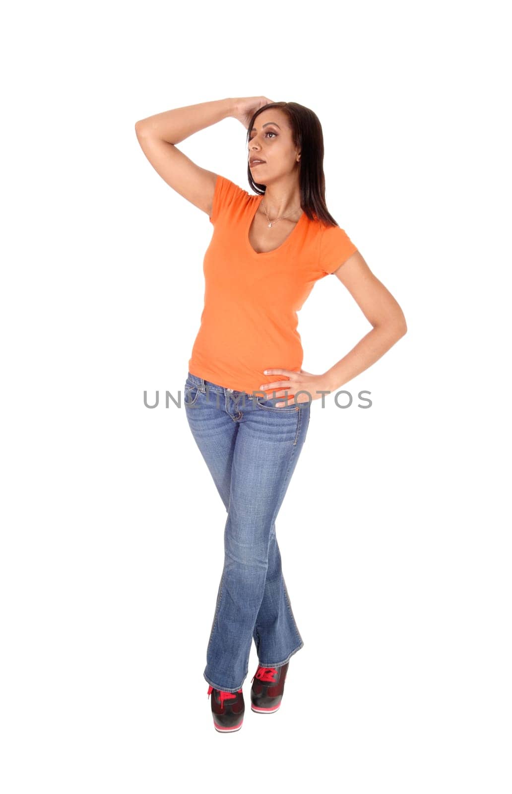 A slim beautiful young woman standing in jeans and a pink?? Top.with one hand on her head, isolated for white background.