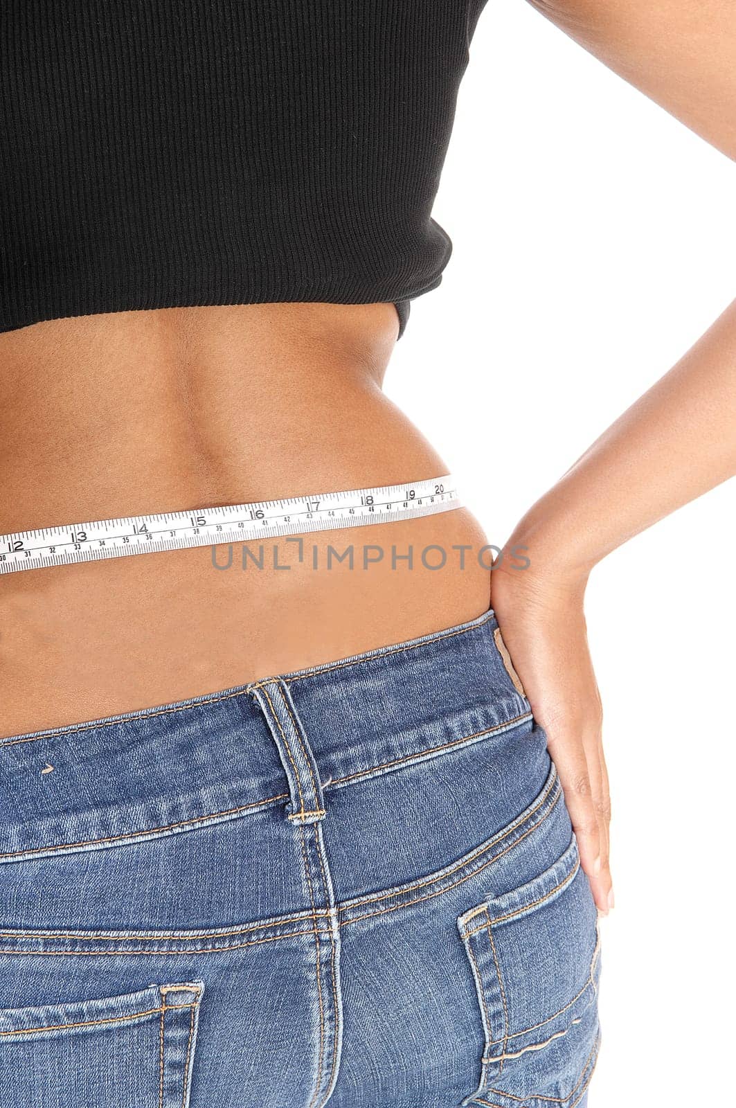 A back side of a young woman in jeans measuring her hip with a white.measuring tape, body part, isolated for white background.