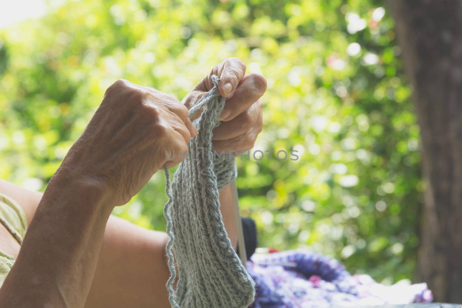 The old woman knits woolen clothes. Close-up of hands knitting. Knitting needles.