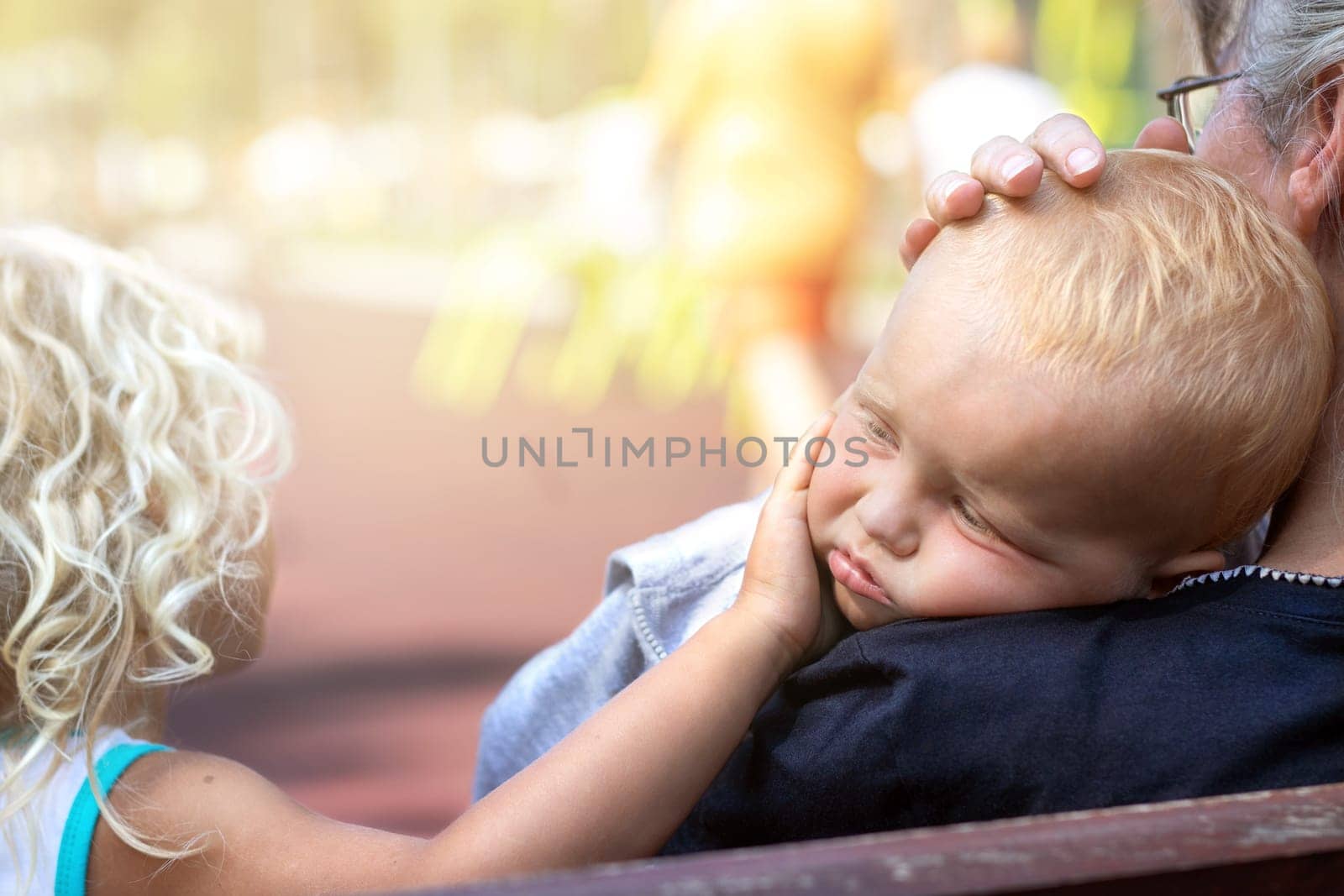 Grandmother and sister hugging and comfort the upset kid in the playground