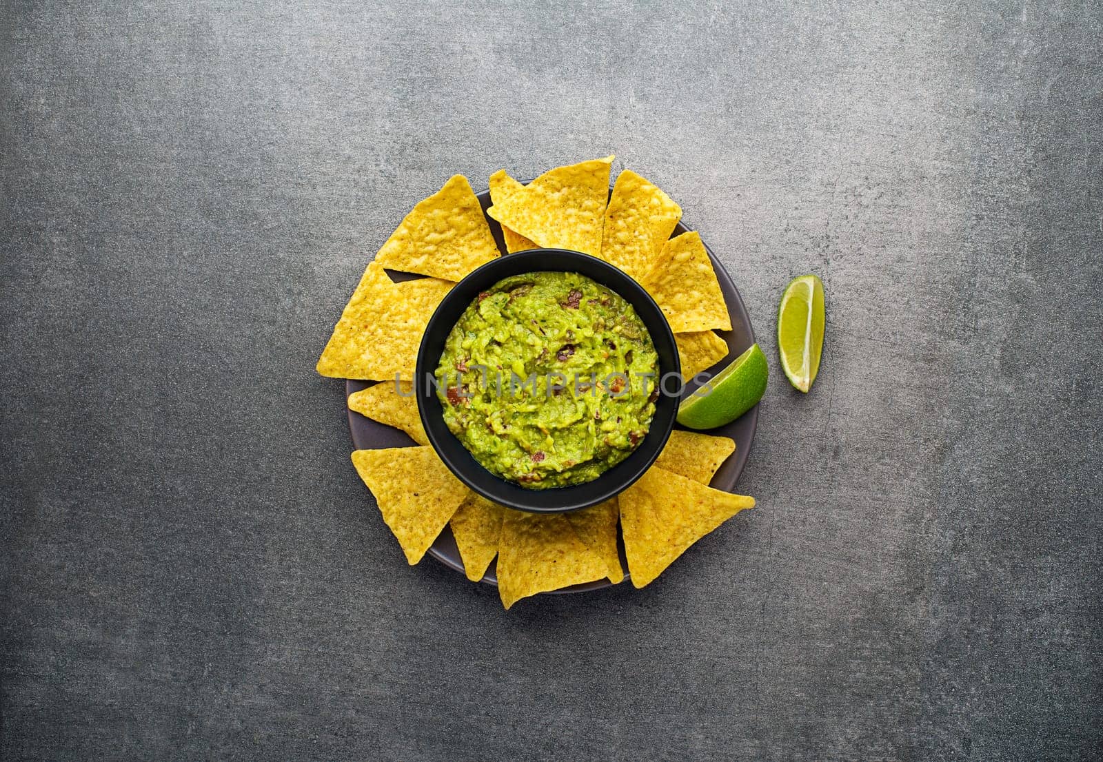 Guacamole sauce with fresh ingredients and corn nachos chips on plate