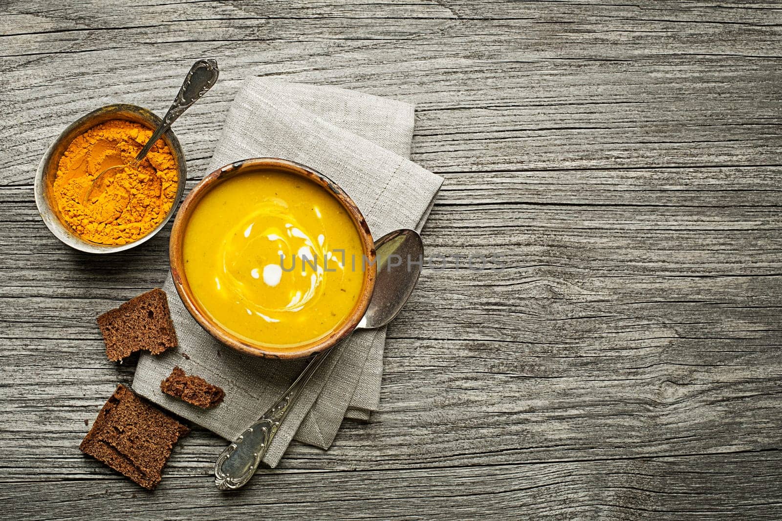 Healthy turmeric or curcuma cream soup on wooden background
