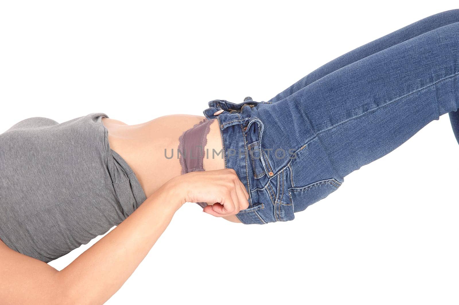 A slim young woman lying on the floor in panties and try to pull up.her jeans, body part, isolated for white background.