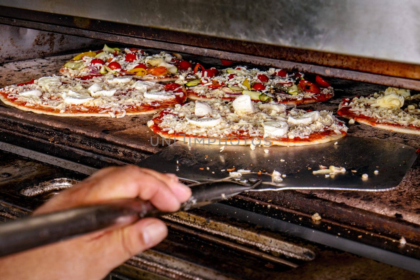 Chef putting pizza ready for baking in the electric oven