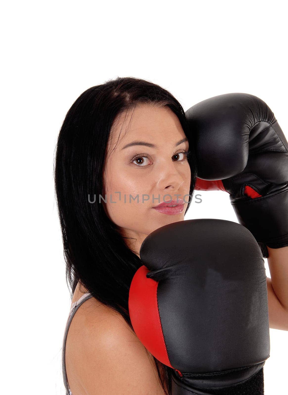 A young woman looking into the camera with her black boxing cloves.and black hair, ready for the fight, isolated for white background.