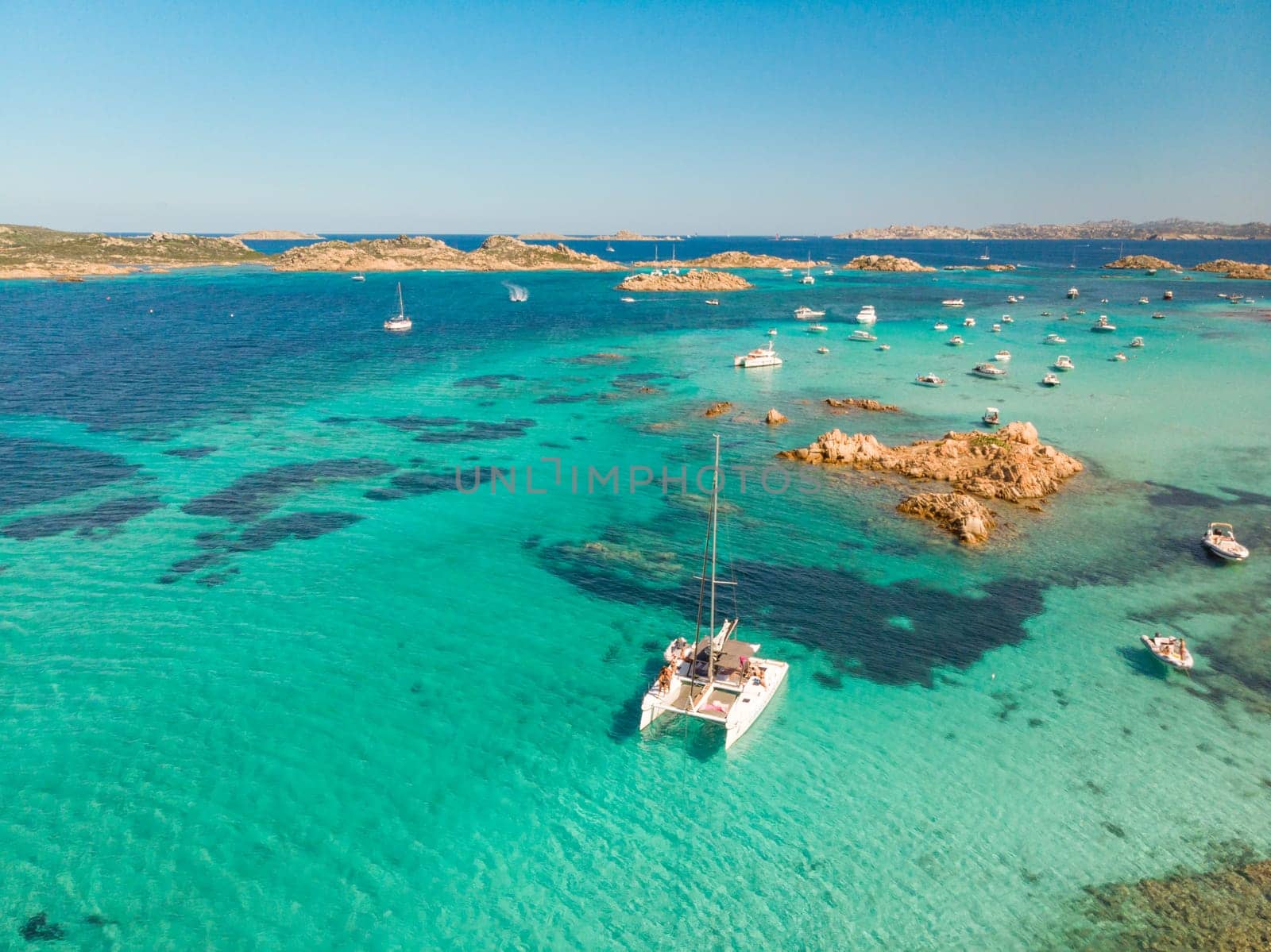 Drone aerial view of catamaran sailing boat in Maddalena Archipelago, Sardinia, Italy. Maddalena Archipelago is composed of Razzoli, Santa Maria and Budelli islands.