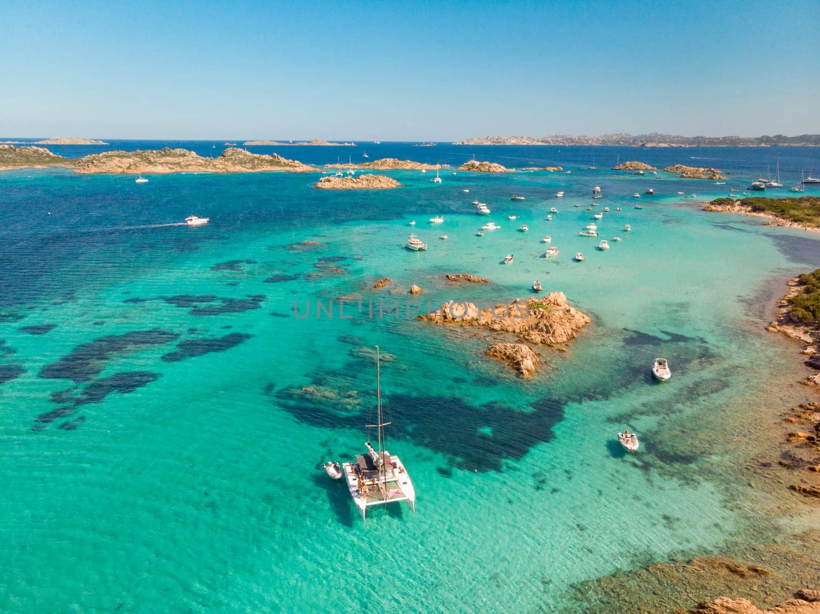 Drone aerial view of catamaran sailing boat in Maddalena Archipelago, Sardinia, Italy. Maddalena Archipelago is composed of Razzoli, Santa Maria and Budelli islands.