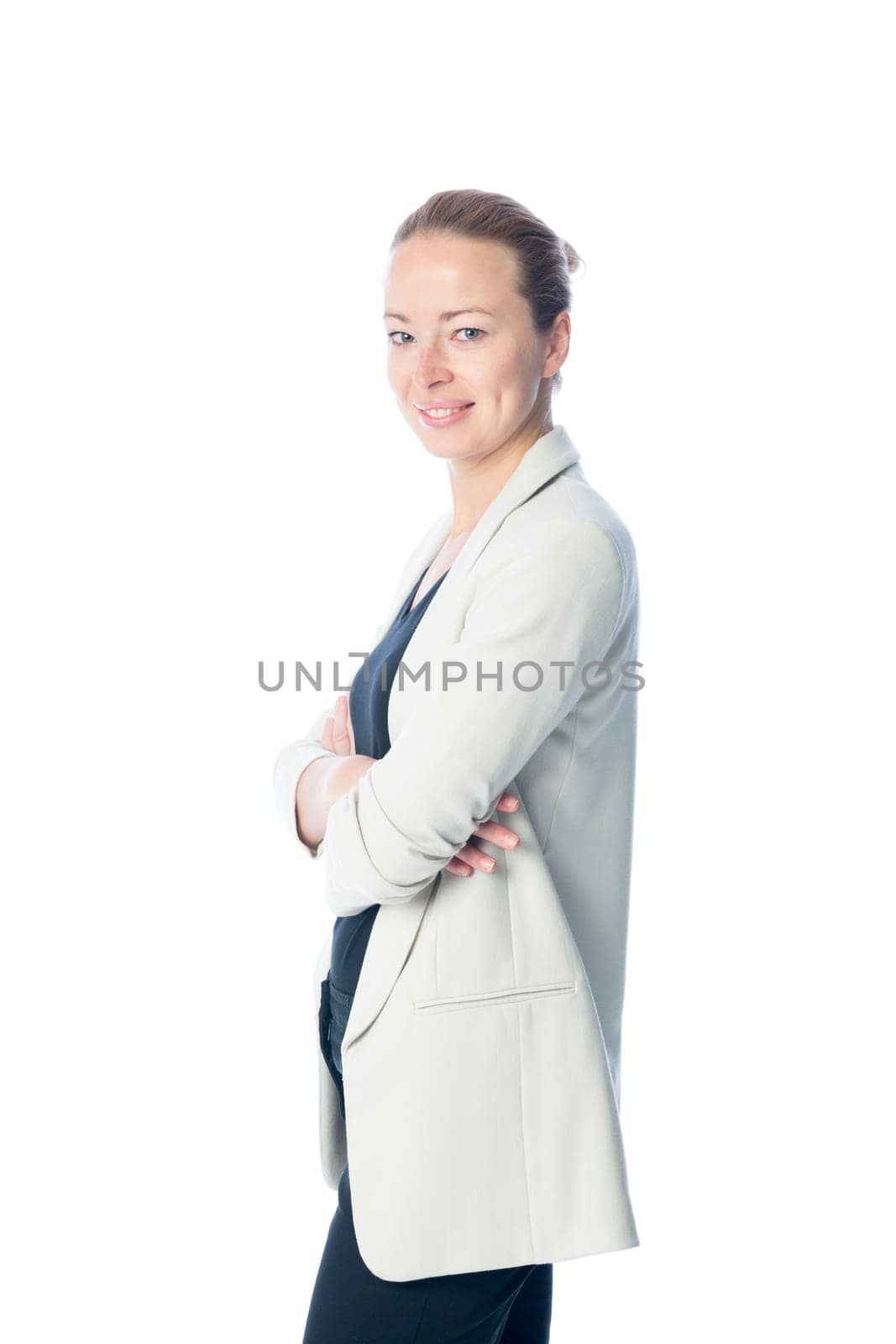 Full body side portrait of casualy dressed,cheerful, beautiful, smart, young businesswoman in standing with arms crossed against white background.