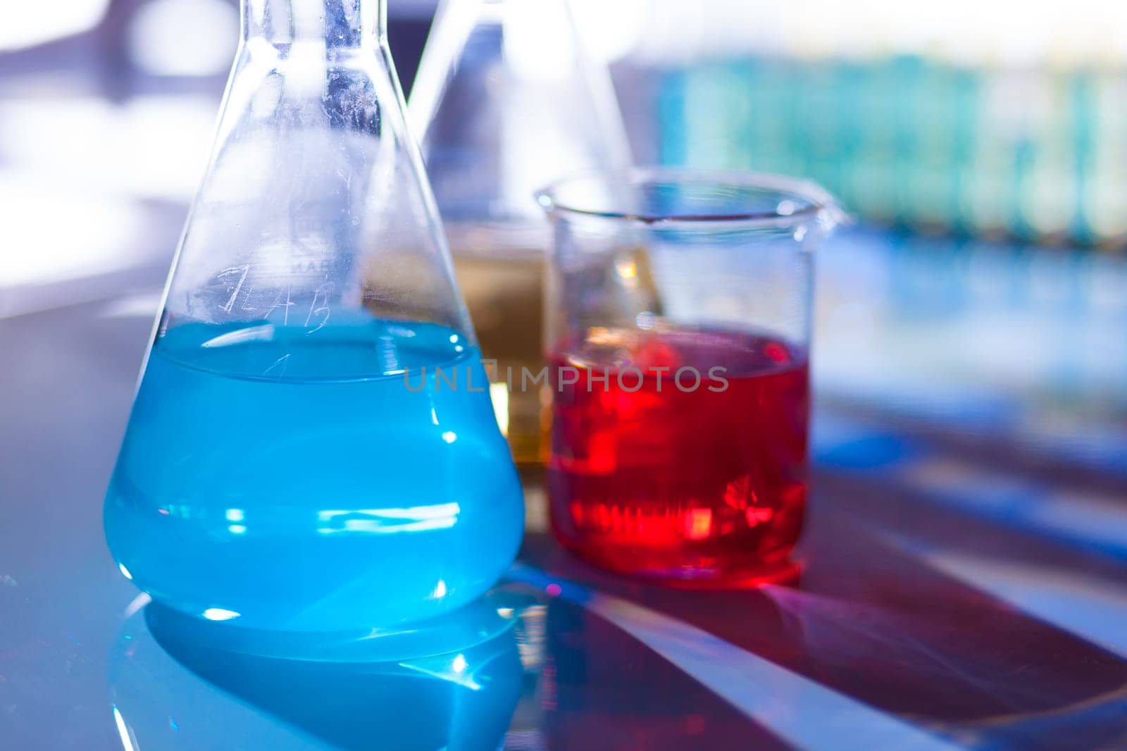 Backlit laboratory test flask containing colorful liquids.