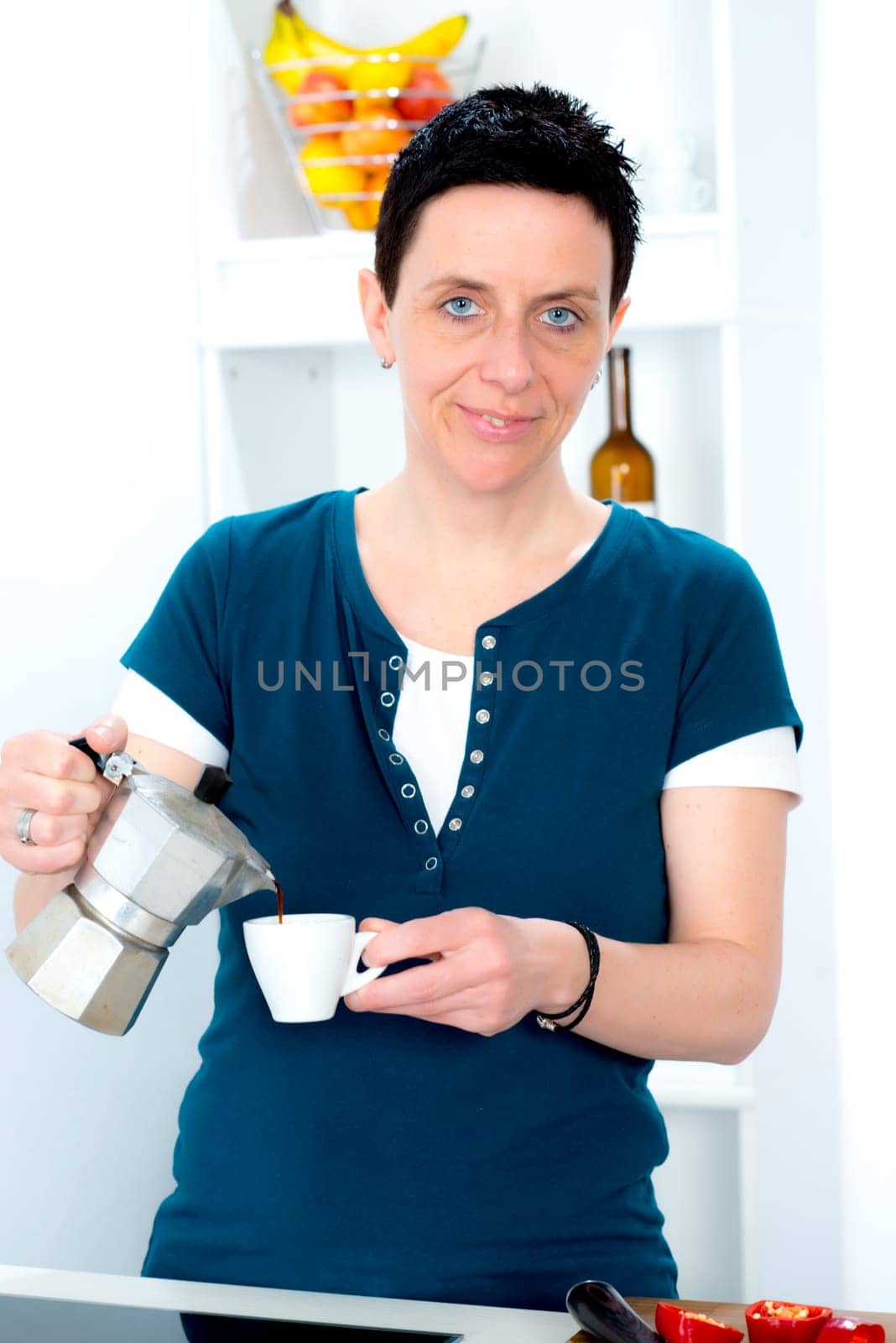 woman with short dark hair is drinking coffee in the kitchen