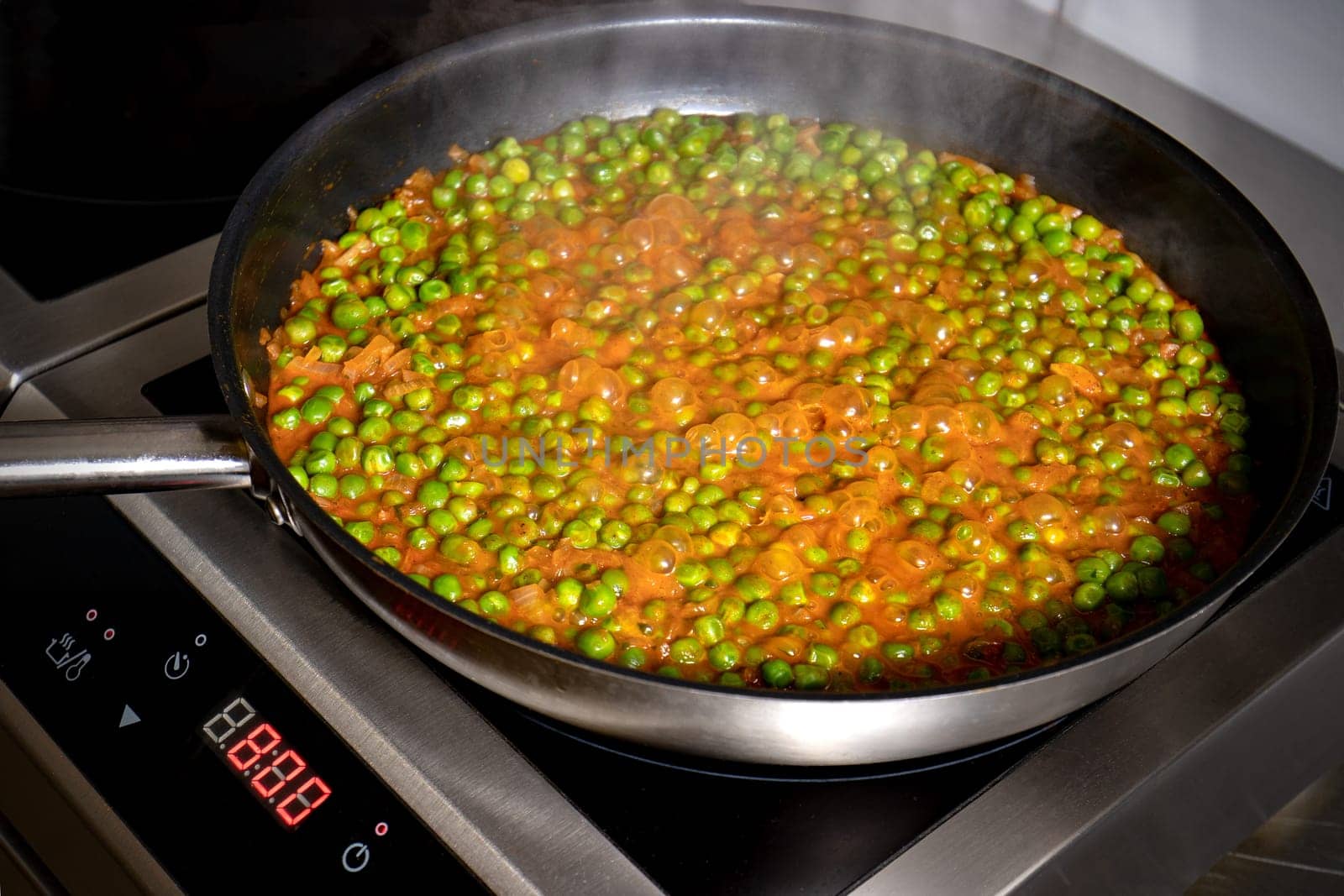 Low peas and tomato sauce boiled in the pan on the electric hob