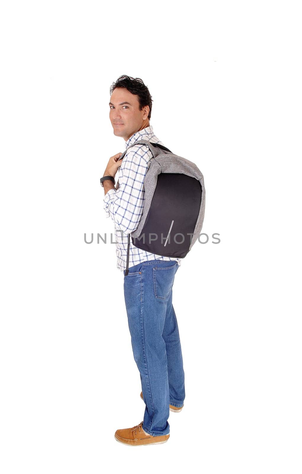 A handsome young man standing in profile looking into the camera.with his backpack on his back, isolated for white background.