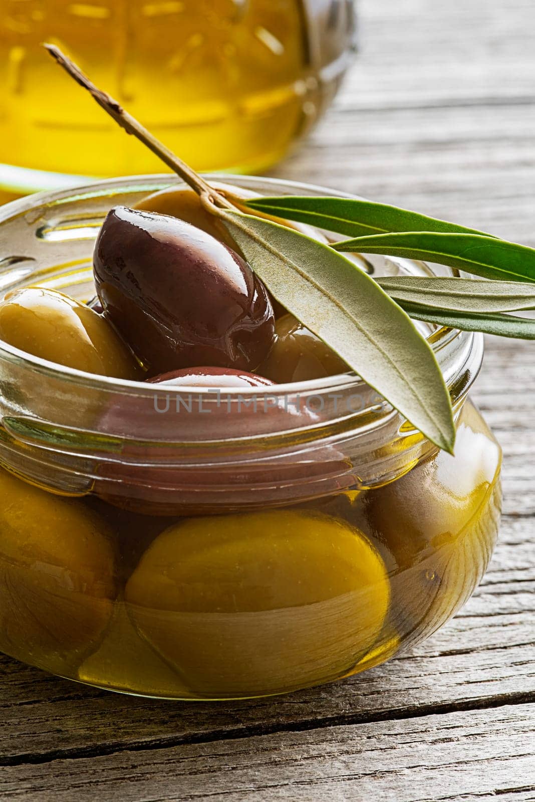 Olive oil in glass bowl with fresh olives fruit