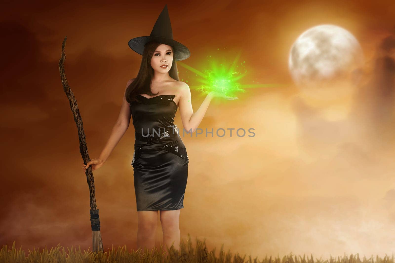 Pretty asian witch woman with broomstick and magic fire on her hand. Halloween concept