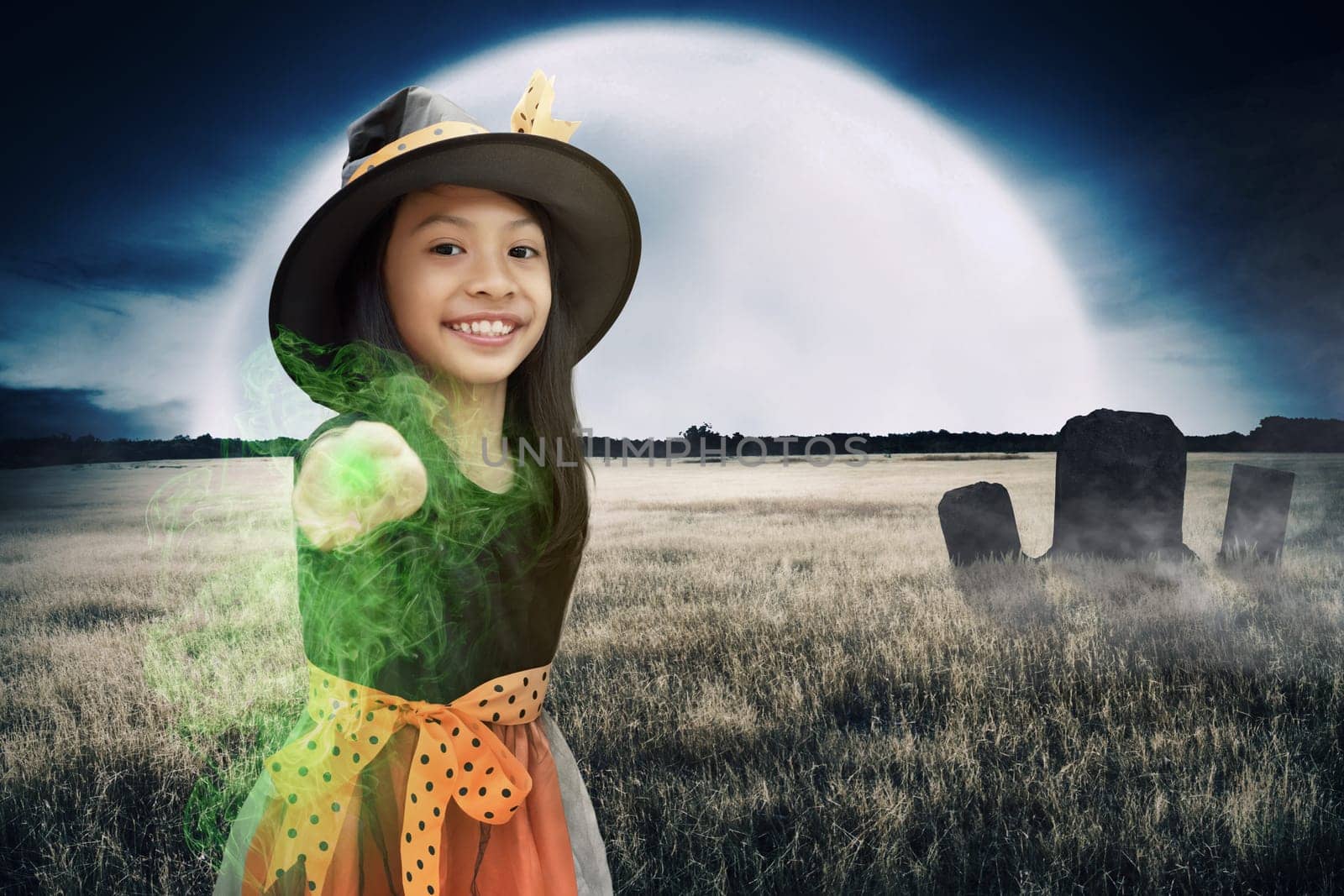 Cheerful asian witch child girl use magic wand power. Halloween concept