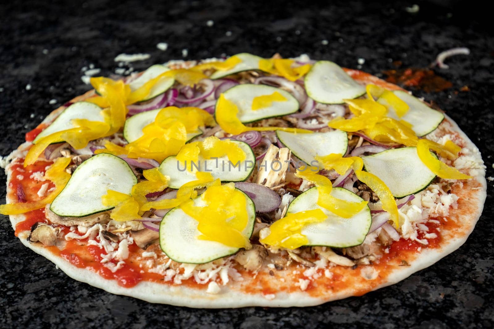Vegetarian pizza on black table, ready to be baked