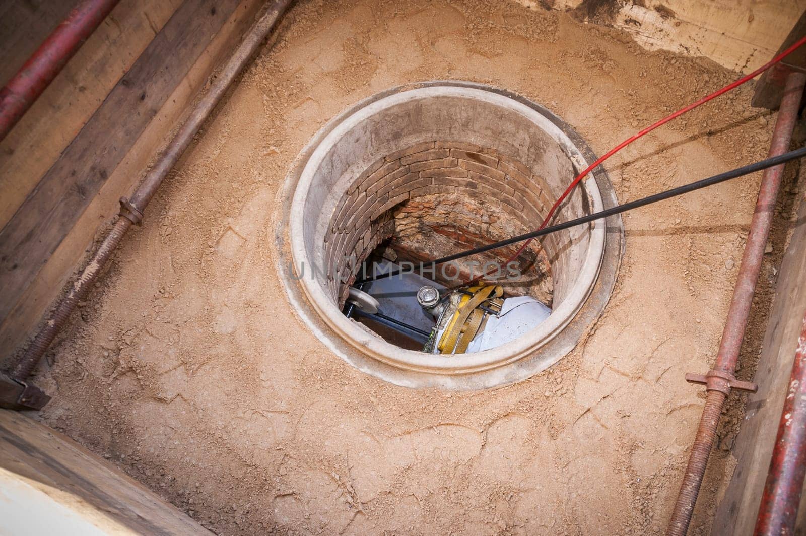 Rehabilitation work on an exposed sewer with manhole and automatic feed device for lining the canal.