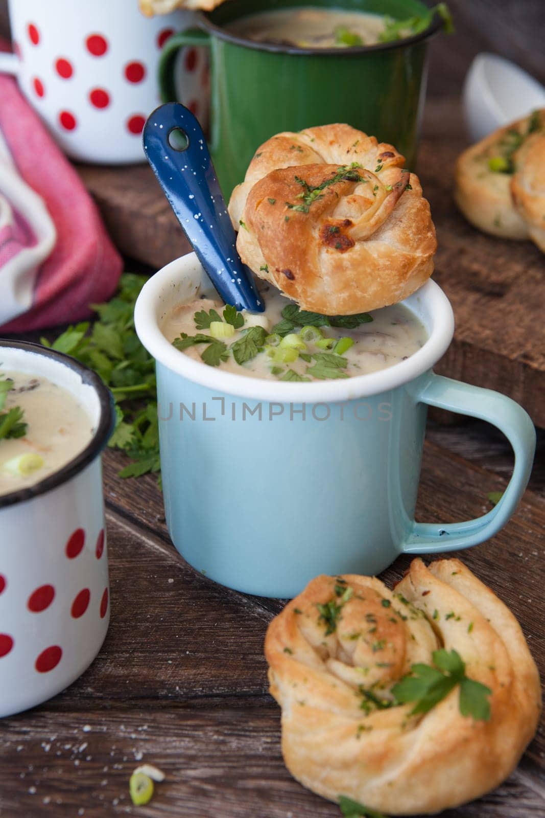 Creamy mushroom soup with fresh parley in rustic enamel mugs