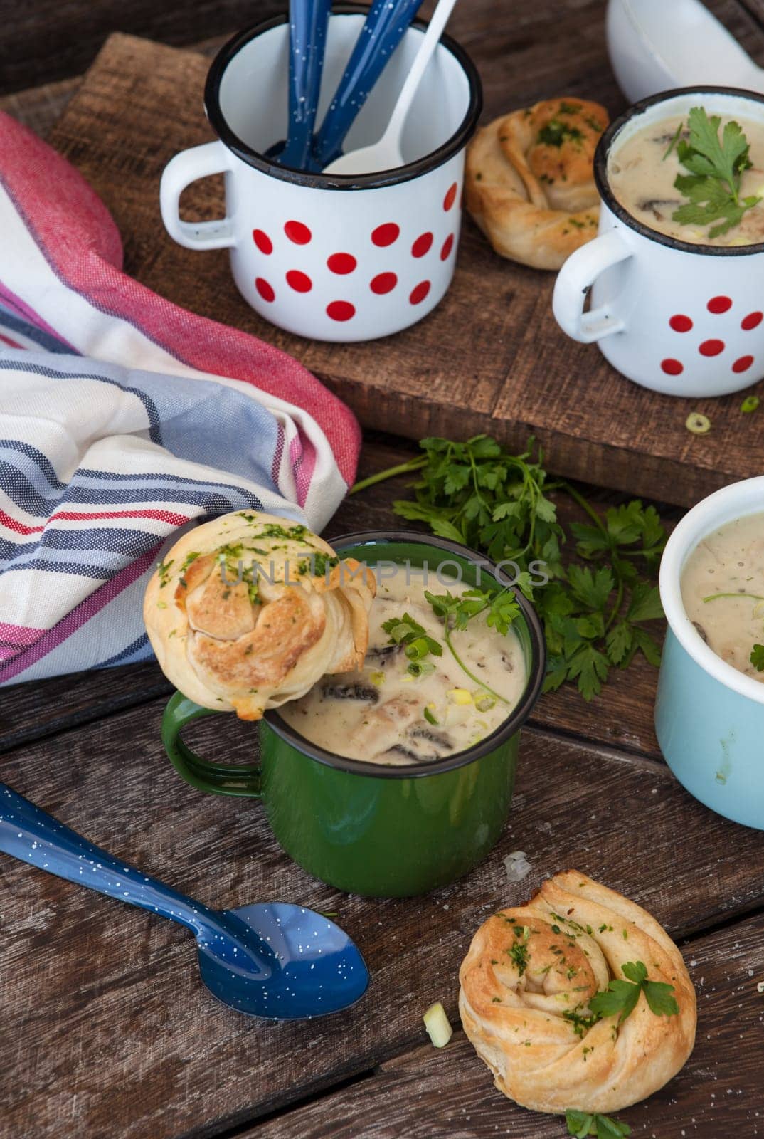 Creamy mushroom soup with fresh parley in rustic enamel mugs