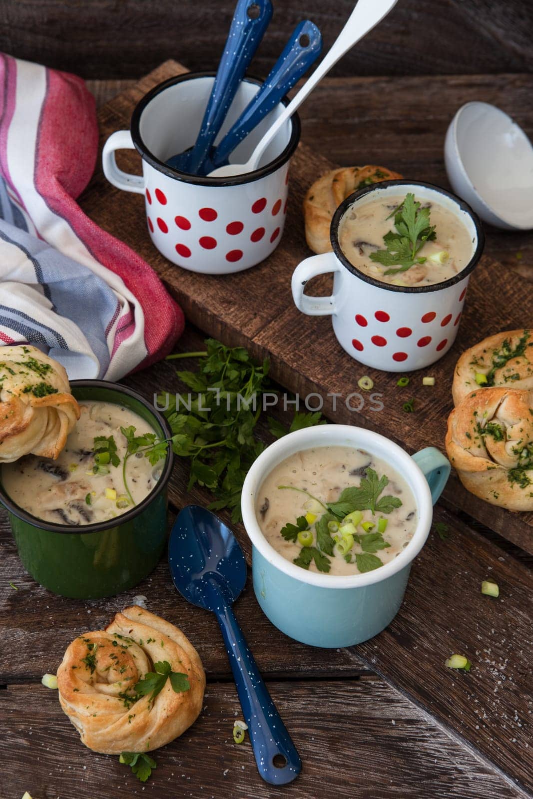 Creamy mushroom soup with fresh parley in rustic enamel mugs