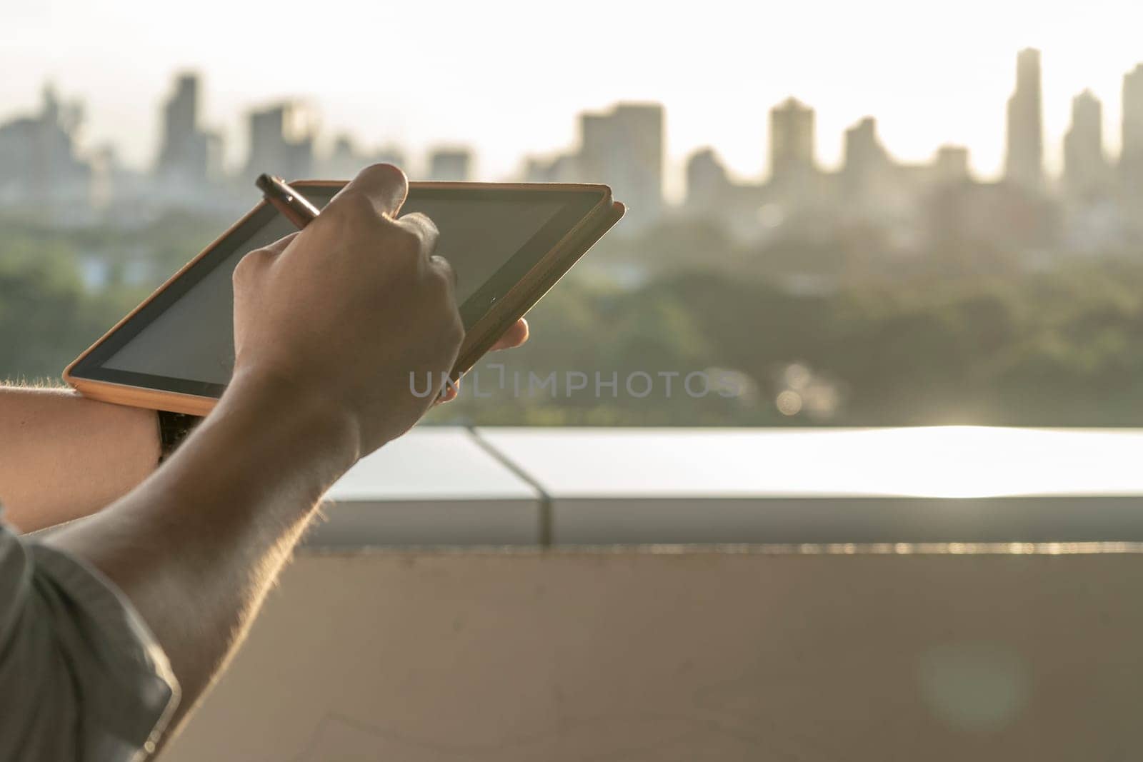 Hands holding tablet building background in the morning.