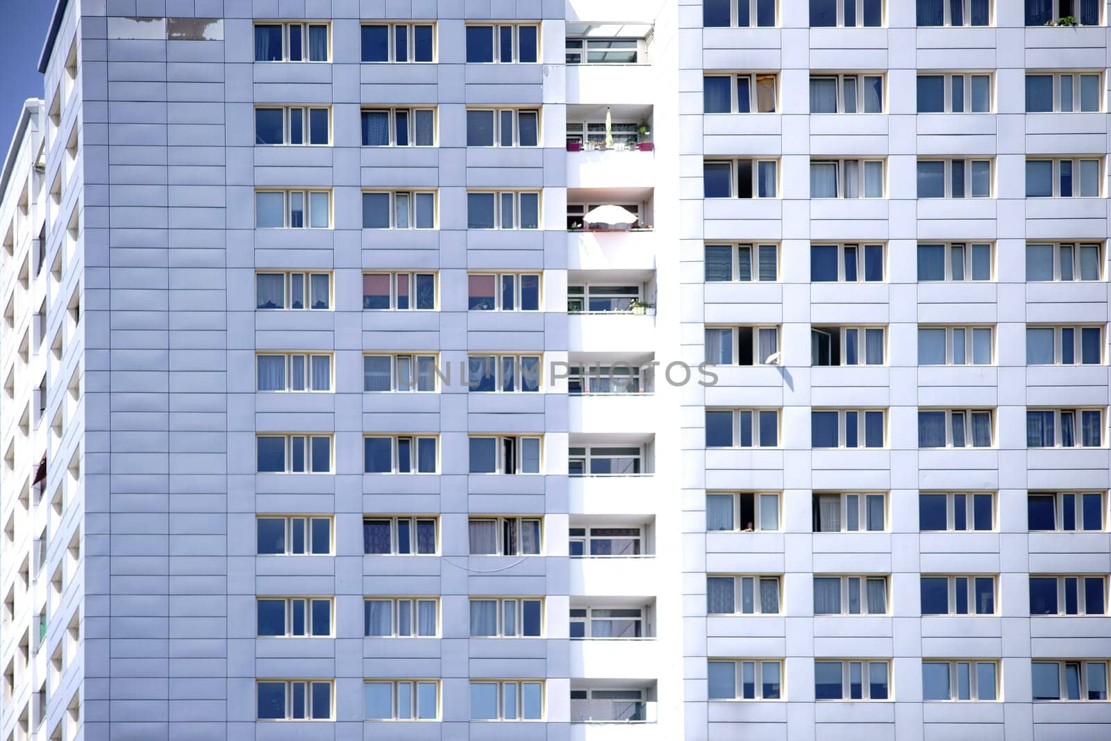 The window front of a skyscraper with apartments and balconies.