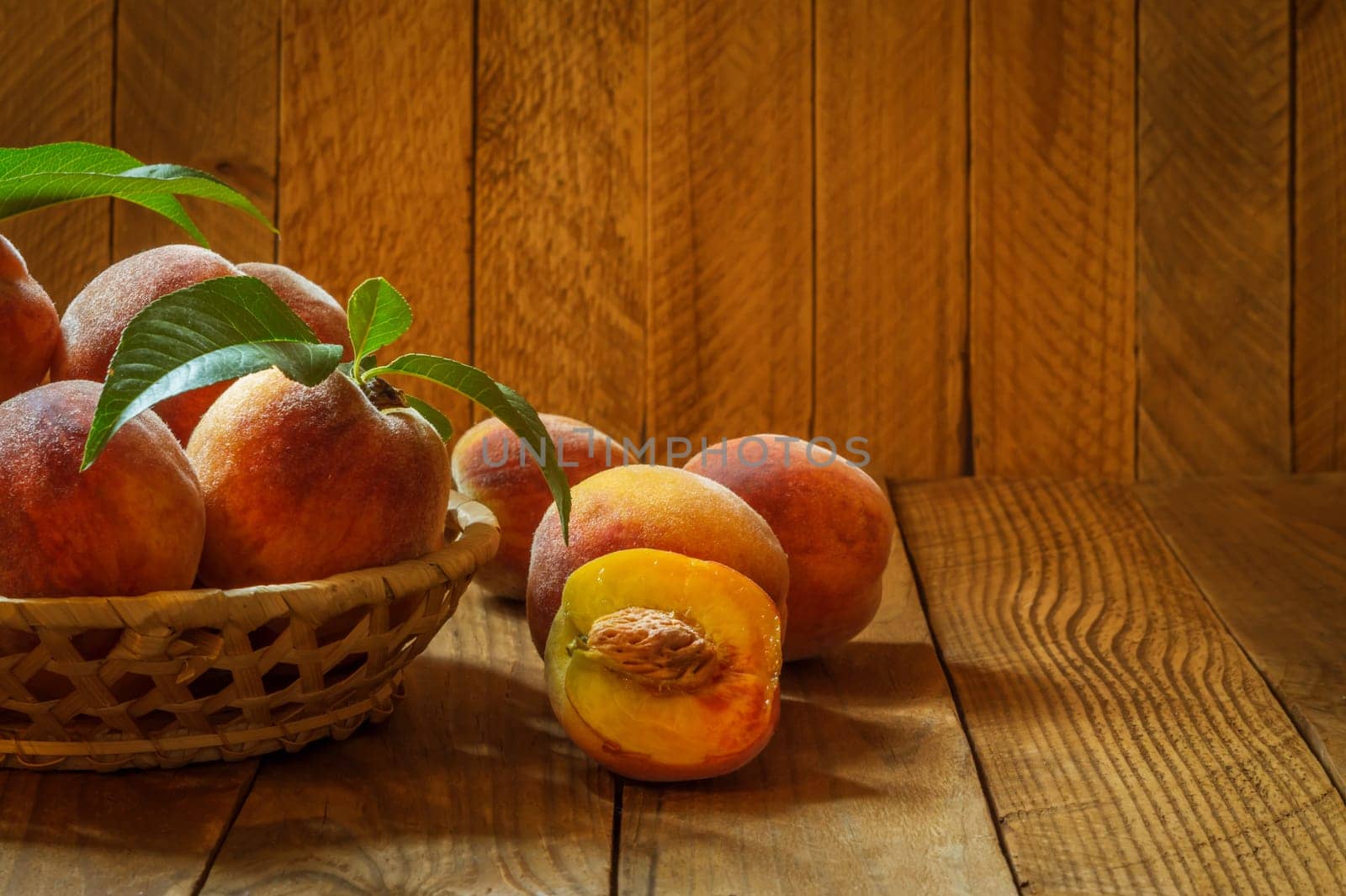 Ripe and beautiful peaches in a basket on a wooden background.
