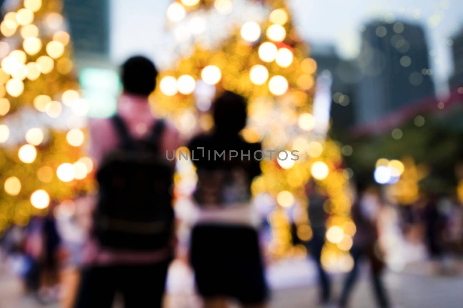 Conceptual defocused Christmas decoration and crowd of people on city street at night