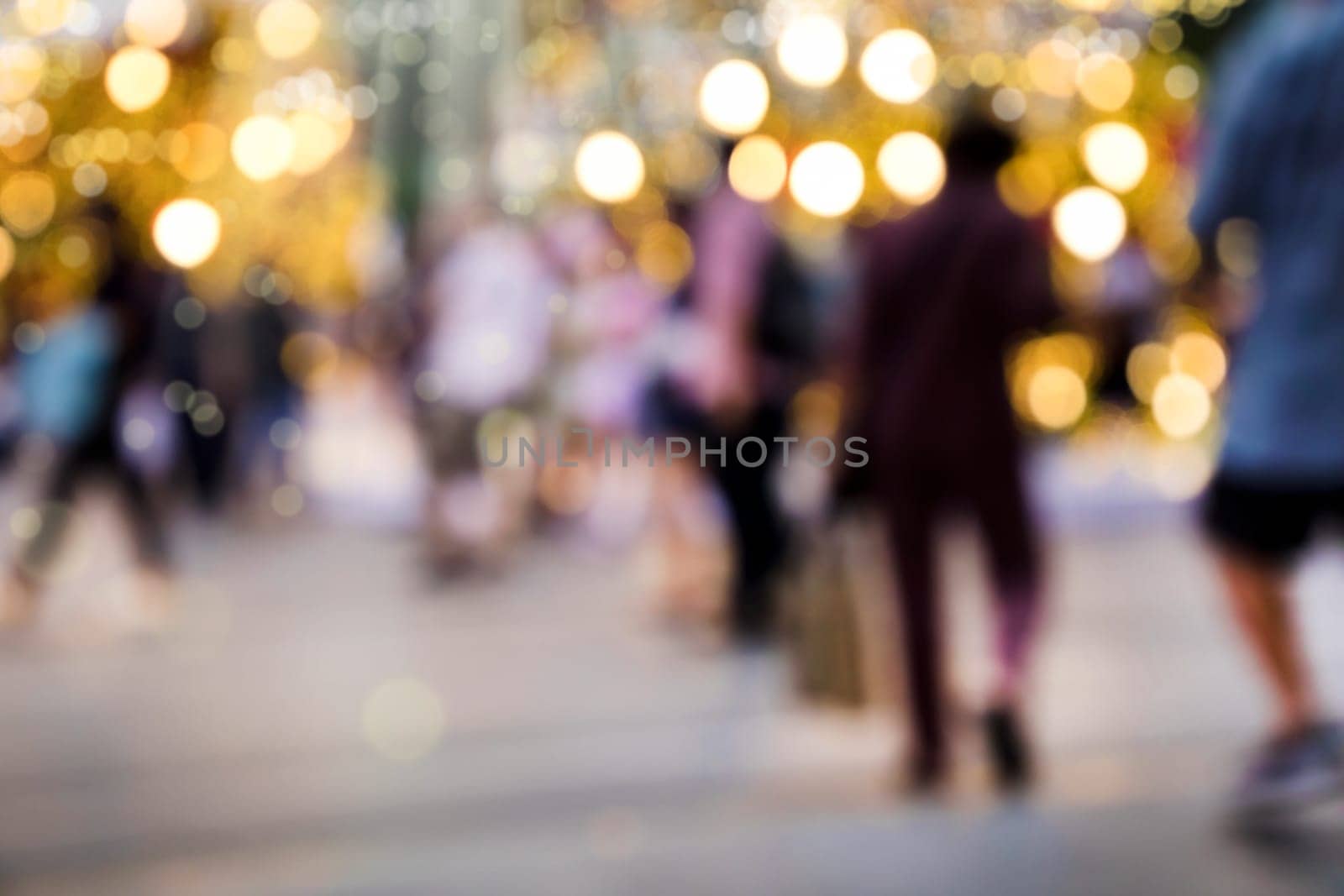 Conceptual defocused Christmas decoration and crowd of people on city street at night