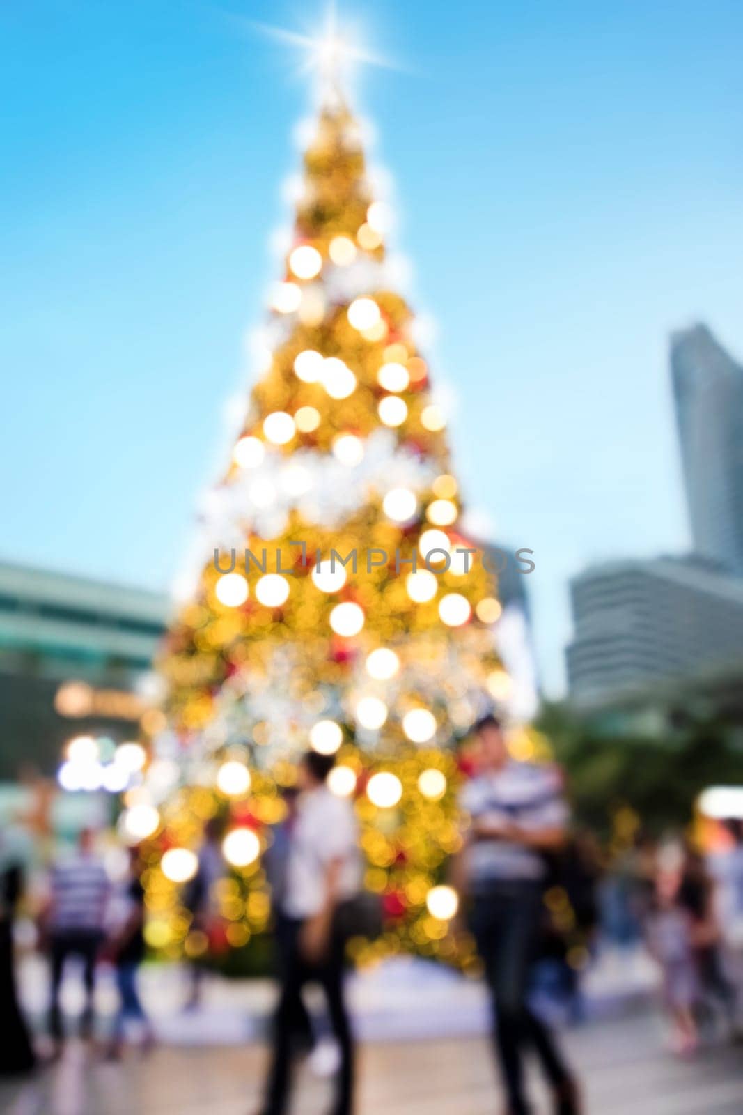 Conceptual defocused abstract decorated Christmas Tree and crowd of people on city street at night