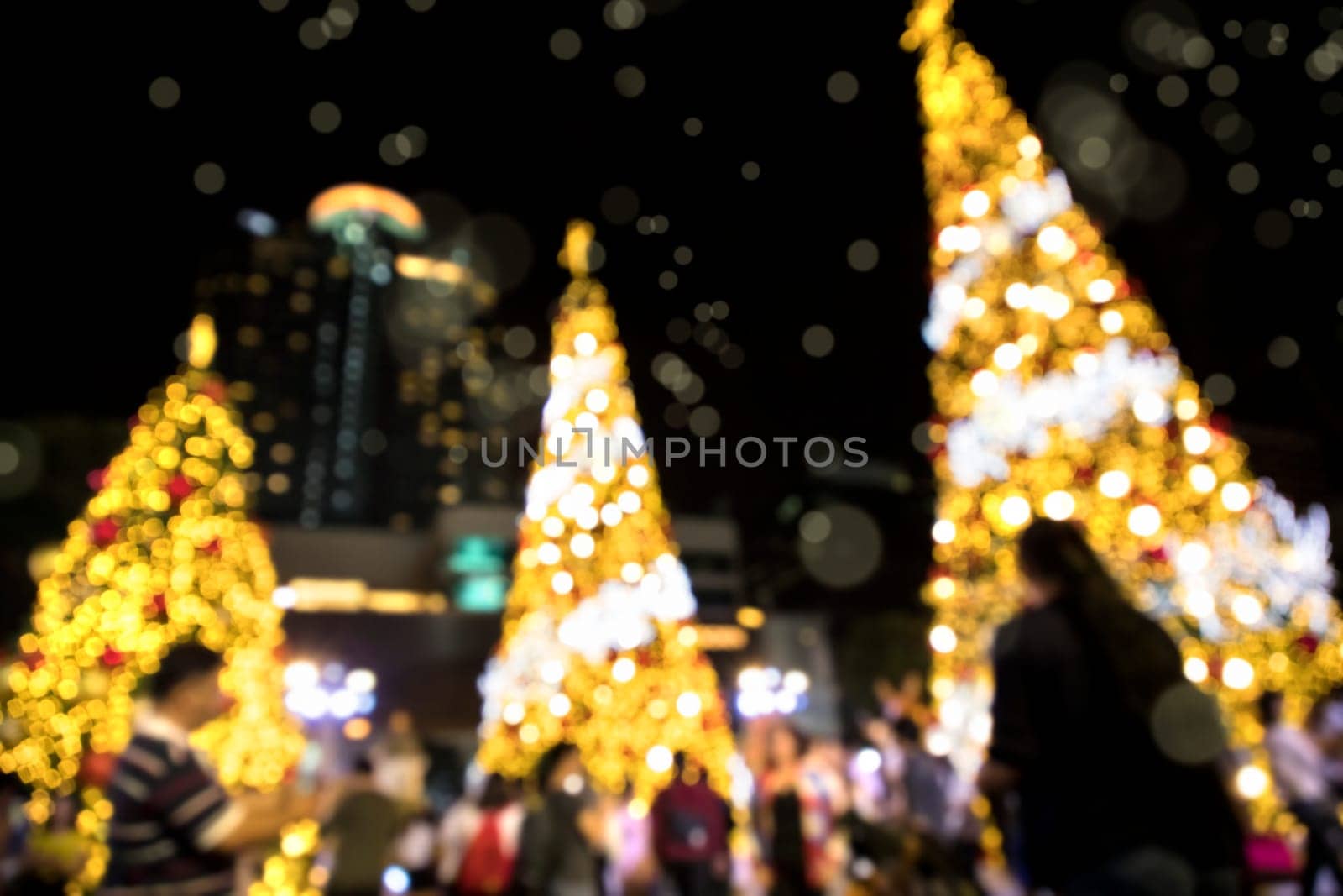 Conceptual defocused abstract decorated Christmas Tree and crowd of people on city street at night