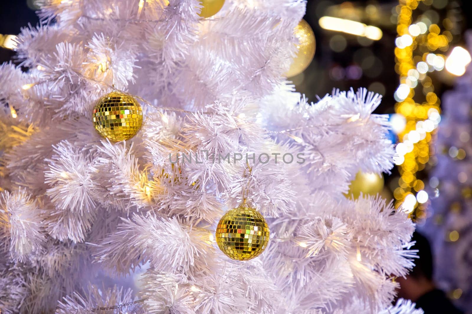 Conceptual image of decorated outdoor white Christmas tree with colorful lights and ornaments