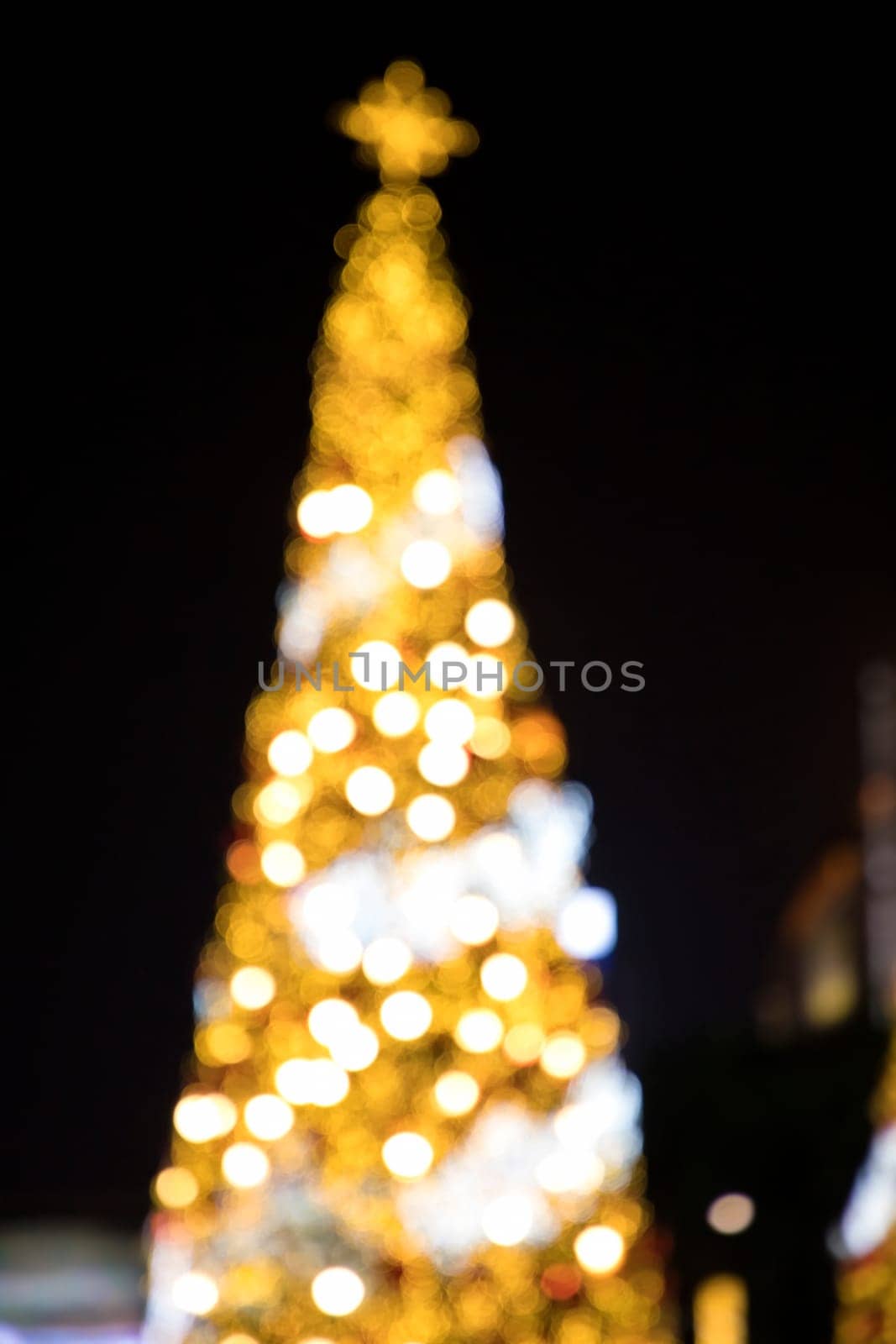 Conceptual background image of defocused abstract Christmas Tree on city street at night