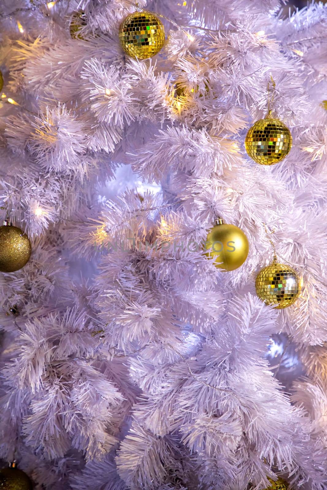 Conceptual image of decorated outdoor white Christmas tree with colorful lights and ornaments