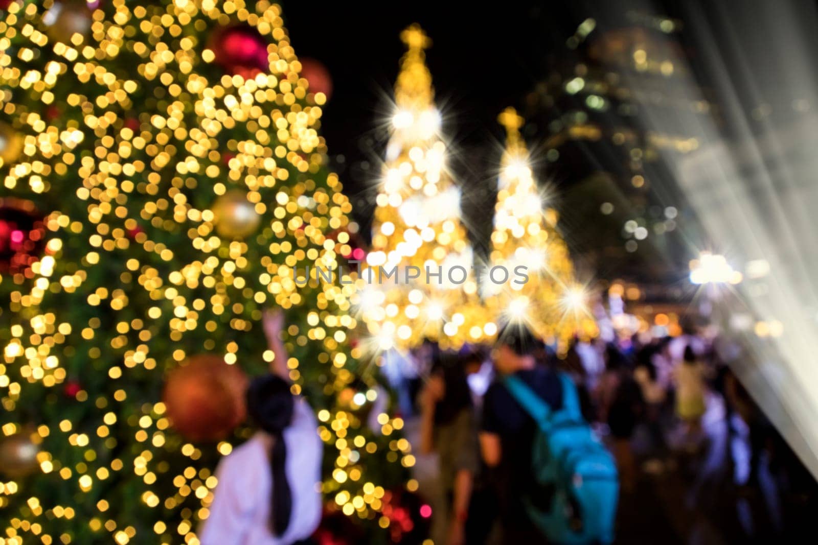 Conceptual defocused abstract decorated Christmas Tree and crowd of people on city street at night