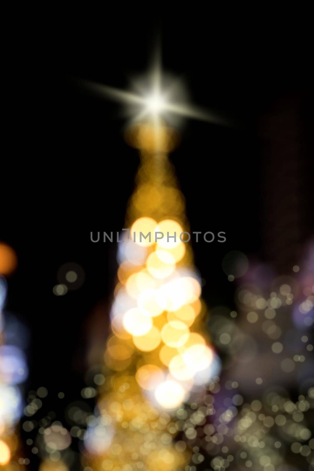 Conceptual background image of defocused abstract Christmas Tree on city street at night